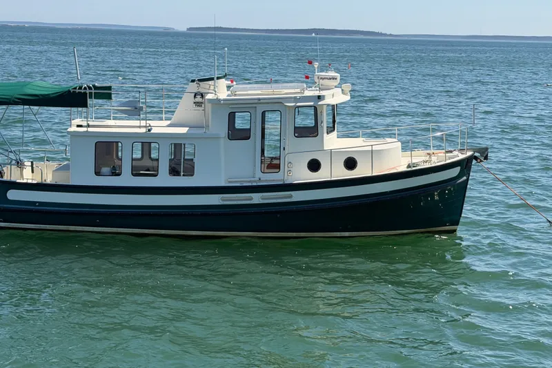 Slide: The Image of 2001 Nordic Tug 32 boat on calm blue water, side view. - 2