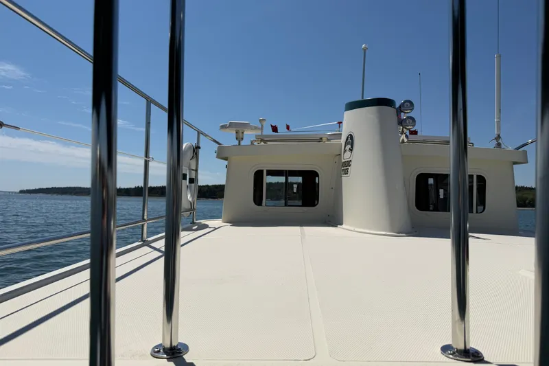 Slide: The Image of 2001 Nordic Tug 32 boat deck with railing, cruising on calm waters under clear skies. - 11