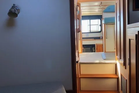 Slide: The Image of Interior view of a 2001 Nordic Tug 32 boat, featuring wooden steps and bright cabin lighting. - 73