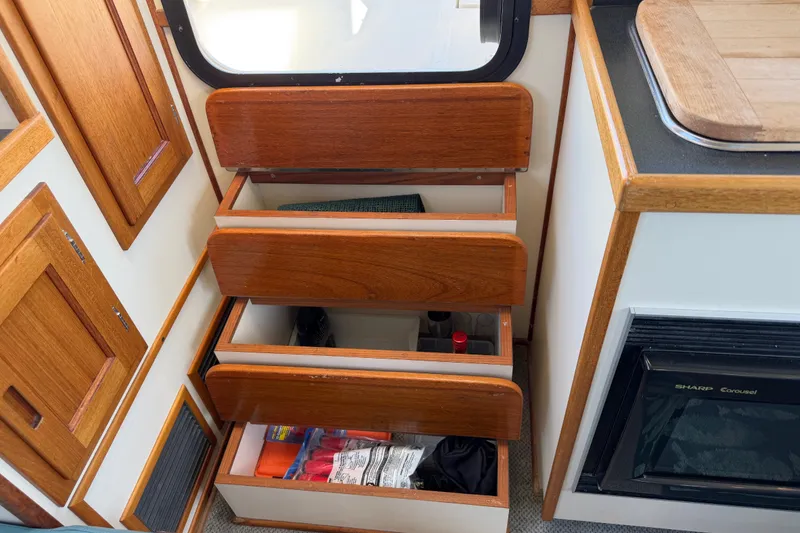 Slide: The Image of Wooden drawers and cabinets inside a 2001 Nordic Tug 32 boat galley. - 59