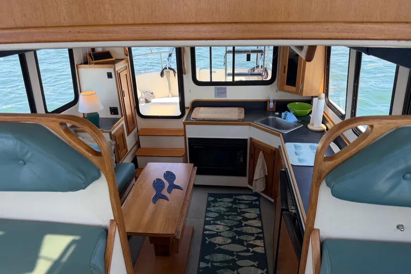 Slide: The Image of Interior of 2001 Nordic Tug 32, featuring cozy seating and compact kitchen area. - 23