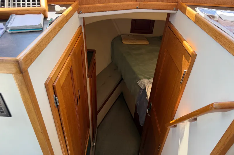 Slide: The Image of Interior cabin of a 2001 Nordic Tug 32, featuring wooden doors and cozy sleeping area. - 55