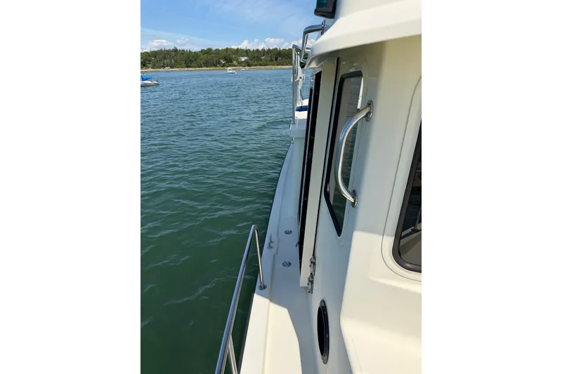 Slide: The Image of 2001 Nordic Tug 32 on calm water, showcasing side deck and railing. - 22