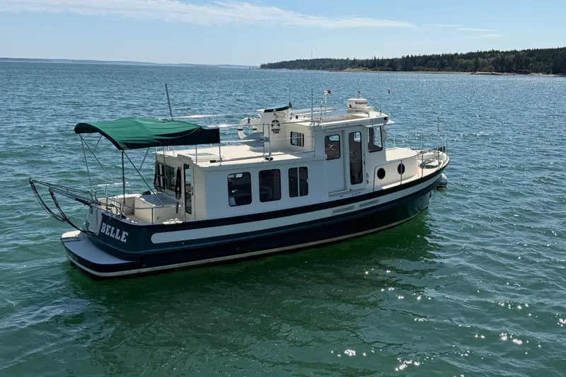 Slide: The Image of 2001 Nordic Tug 32 boat named "Belle" on calm water under clear sky. - 84