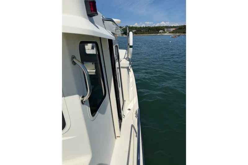 Slide: The Image of 2001 Nordic Tug 32 boat side view on calm water, showcasing sleek design and sturdy build. - 21