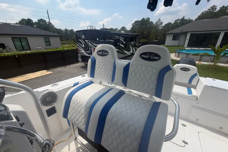 Slide: The Image of 2000 Pro-Line 32 Express boat interior with blue and white seating, parked near a house. - 14