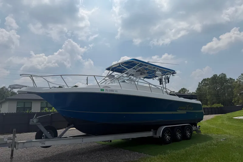 The Image of 2000 Pro-Line 32 Express boat on trailer under cloudy sky. - 0