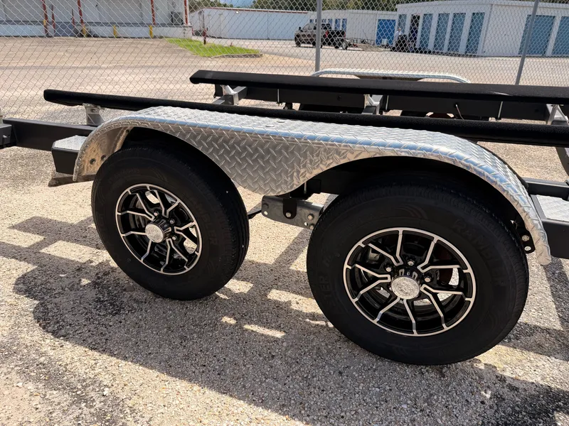 Slide: The Image of A boat trailer with two wheels and a diamond-patterned fender is parked on a lot. - 43