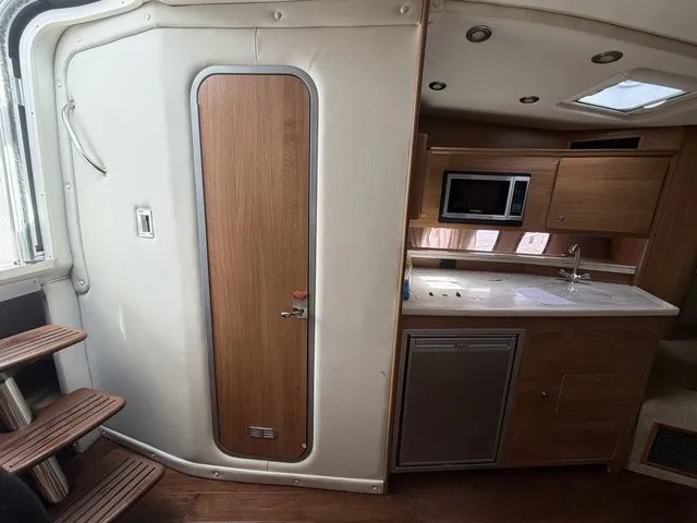 Slide: The Image of Interior of the 2015 Rinker 360 Express Cruiser with kitchenette and wooden door. - 19
