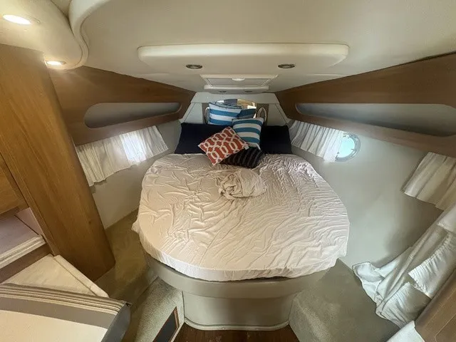 Slide: The Image of The cabin of the 2015 Rinker 360 Express Cruiser features a cozy bed with pillows. - 18