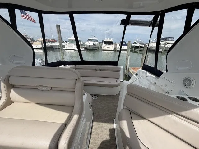 Slide: The Image of Interior of a 2015 Rinker 360 Express Cruiser with beige seating and marina view. - 13