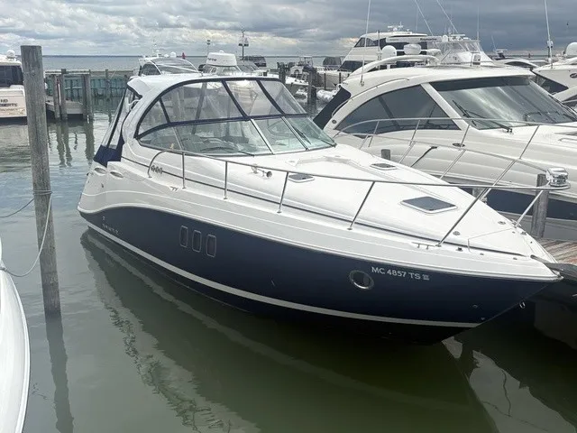 The Image of A 2015 Rinker 360 Express Cruiser docked in a marina. It features a sleek design with an enclosed cockpit. - 1