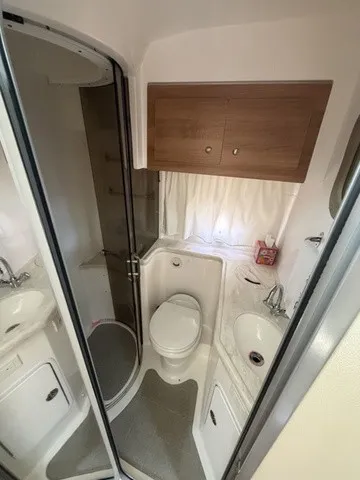 Slide: The Image of The image shows the bathroom of a 2015 Rinker 360 Express Cruiser with a shower, toilet, and sink. - 20