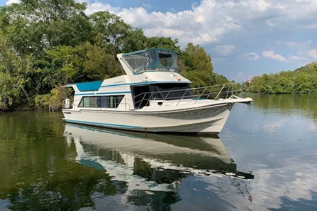 The Image of 1993 Harbor Master 450 Coastal Cruiser on tranquil water, surrounded by lush greenery. - 0