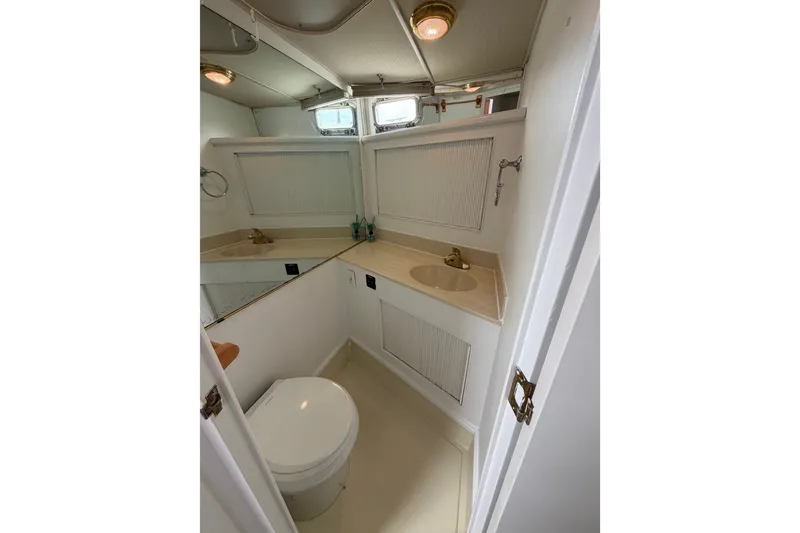 Slide: The Image of 1988 Tollycraft 44 Cockpit Motor Yacht bathroom with sink, toilet, and mirrored cabinet. - 36