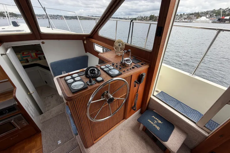 Slide: The Image of 1988 Tollycraft 44 Cockpit Motor Yacht helm with classic wooden steering wheel and navigation instruments. - 25
