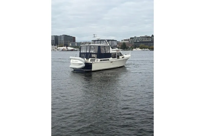 Slide: The Image of 1988 Tollycraft 44 Cockpit Motor Yacht on calm water, cityscape background. - 4