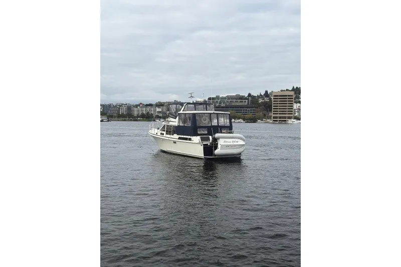 Slide: The Image of 1988 Tollycraft 44 Cockpit Motor Yacht on calm water with cityscape background. - 2