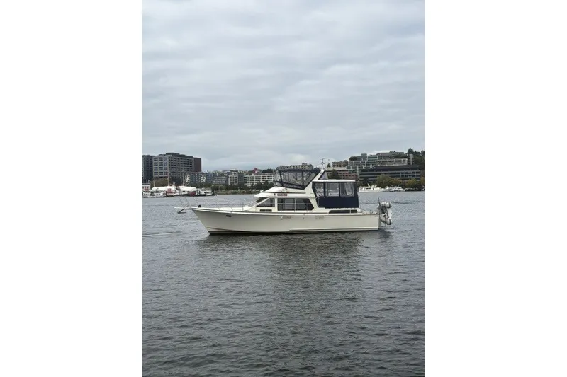 The Image of 1988 Tollycraft 44 Cockpit Motor Yacht on calm water with cityscape background. - 0