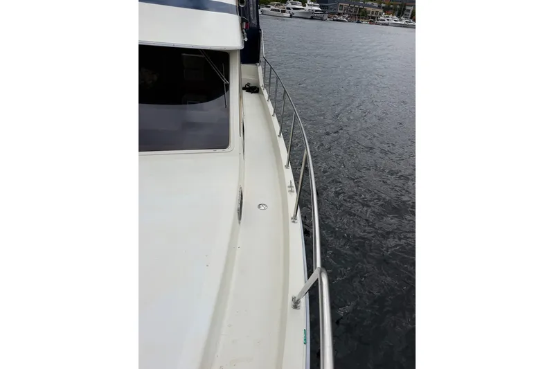Slide: The Image of 1988 Tollycraft 44 Cockpit Motor Yacht deck view, featuring railing and marina backdrop. - 9
