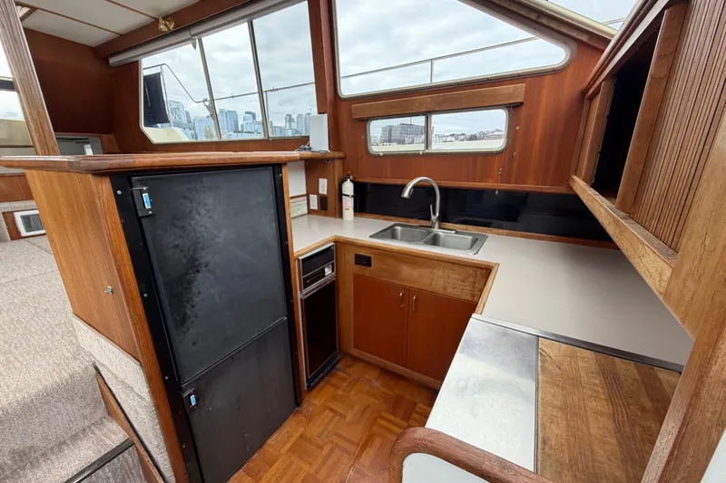 Slide: The Image of 1988 Tollycraft 44 Cockpit Motor Yacht interior kitchen with wood cabinetry and large windows. - 31