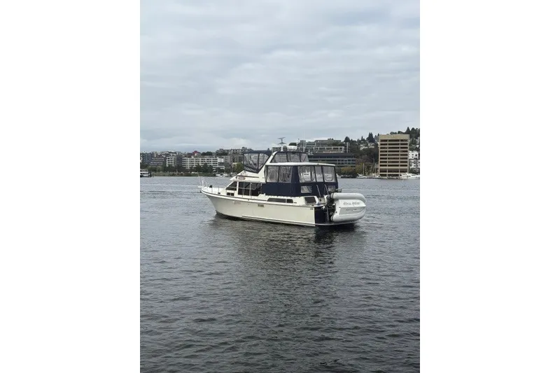 Slide: The Image of 1988 Tollycraft 44 Cockpit Motor Yacht on calm water, cityscape background. - 1