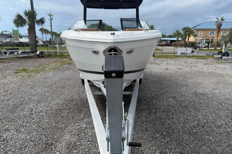 Slide: The Image of 2025 Cobalt R8 Outboard boat on trailer, parked on gravel lot with palm trees. - 1