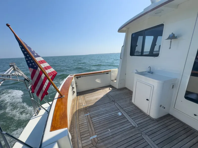 Slide: The Image of The deck of a 2002 Sabre 36 Express with wood accents and an American flag. - 34
