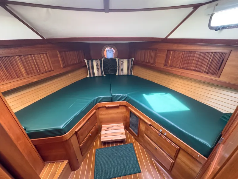 Slide: The Image of The 2002 Sabre 36 Express cabin features a V-shaped bed with green cushions. - 24