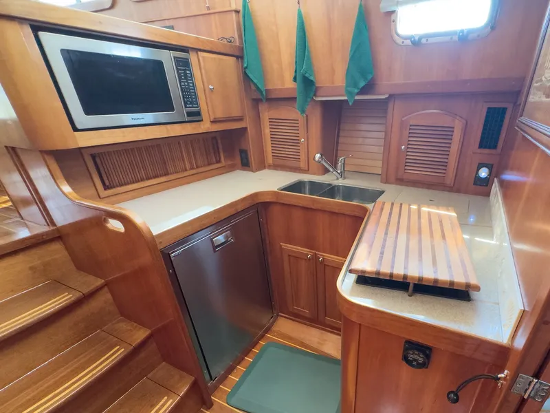 Slide: The Image of The galley of a 2002 Sabre 36 Express with wood paneling, sink, microwave, and refrigerator. - 18