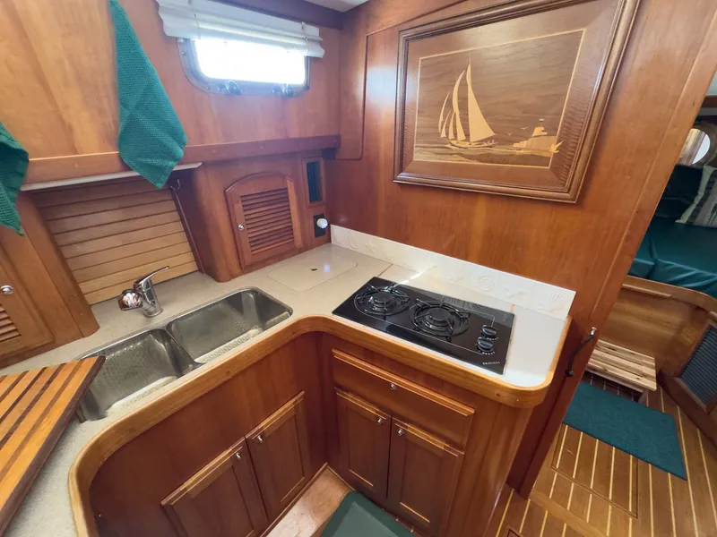 Slide: The Image of The galley of a 2002 Sabre 36 Express with wood paneling and a cooktop. - 20