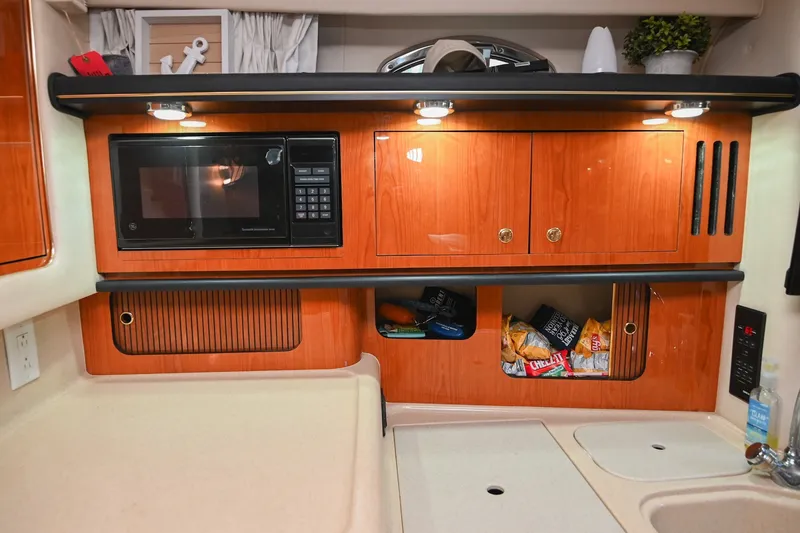 Slide: The Image of 2001 Sea Ray 340 Sundancer galley with microwave, wooden cabinets, and snacks. - 31