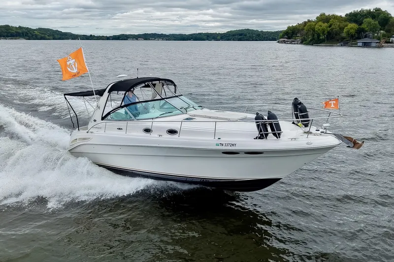 The Image of 2001 Sea Ray 340 Sundancer cruising on a lake with flags, under cloudy skies. - 0