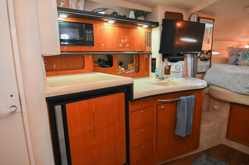 Slide: The Image of 2001 Sea Ray 340 Sundancer interior with kitchenette, microwave, sink, and cozy sleeping area. - 28