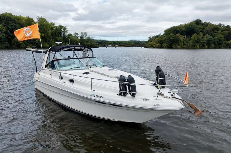 Slide: The Image of 2001 Sea Ray 340 Sundancer boat on a serene lake with lush green surroundings. - 70