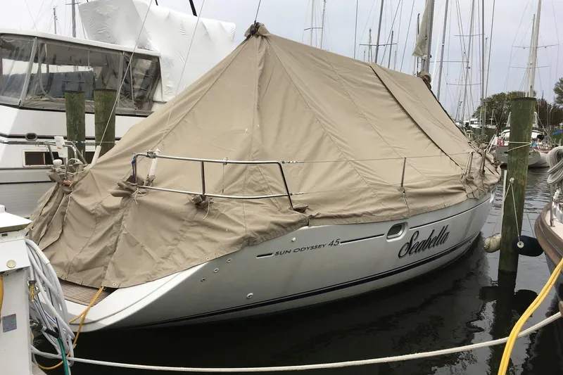 Slide: The Image of 2006 Jeanneau Sun Odyssey 45 sailboat covered with a beige tarp, docked at a marina. - 22