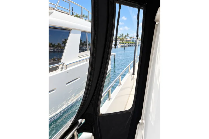 Slide: The Image of 2003 Horizon 62 Motor Yacht view through cabin window, docked by clear blue water. - 62