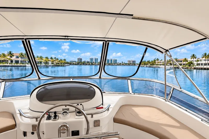 Slide: The Image of Cockpit view from 2003 Horizon 62 Motor Yacht, overlooking serene waterfront and luxury homes. - 63