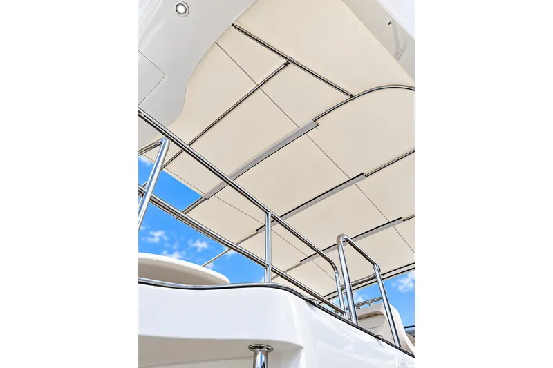 Slide: The Image of 2003 Horizon 62 Motor Yacht with sleek canopy and stainless steel railings against blue sky. - 69