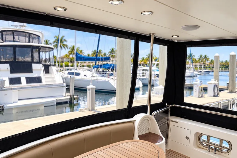 Slide: The Image of 2003 Horizon 62 Motor Yacht interior with marina view, featuring luxurious seating and wooden table. - 68