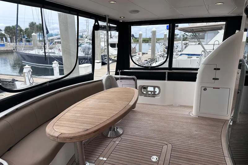 Slide: The Image of Spacious deck of 2003 Horizon E62 Motor Yacht with wooden table and seating. - 83