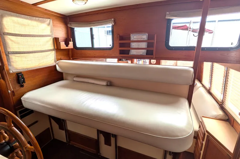 Slide: The Image of Interior of a 1993 Nordic Tug 32, featuring a cushioned seating area and wooden accents. - 35