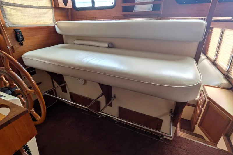 Slide: The Image of Interior of a 1993 Nordic Tug 32, featuring a cushioned bench and wooden accents. - 36