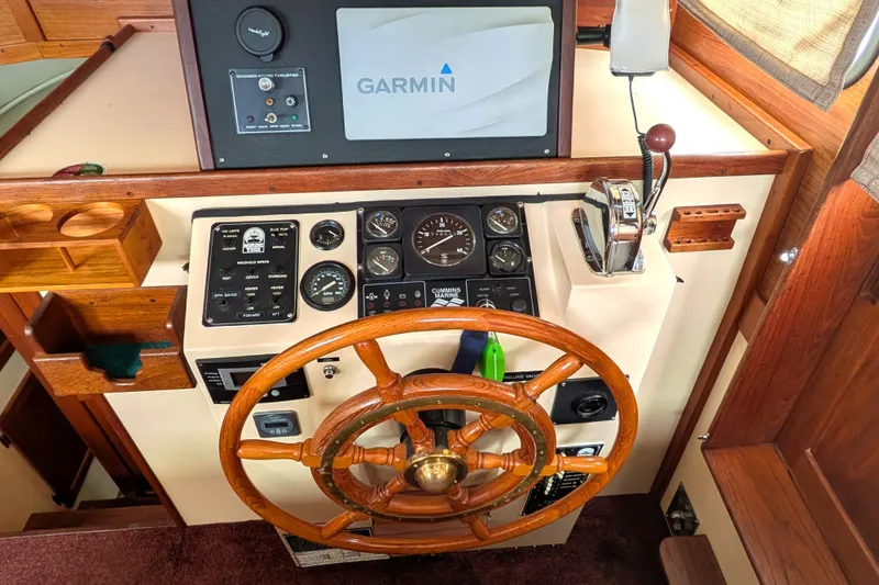 Slide: The Image of 1993 Nordic Tug 32 helm with Garmin navigation, wooden wheel, and control panel. - 24