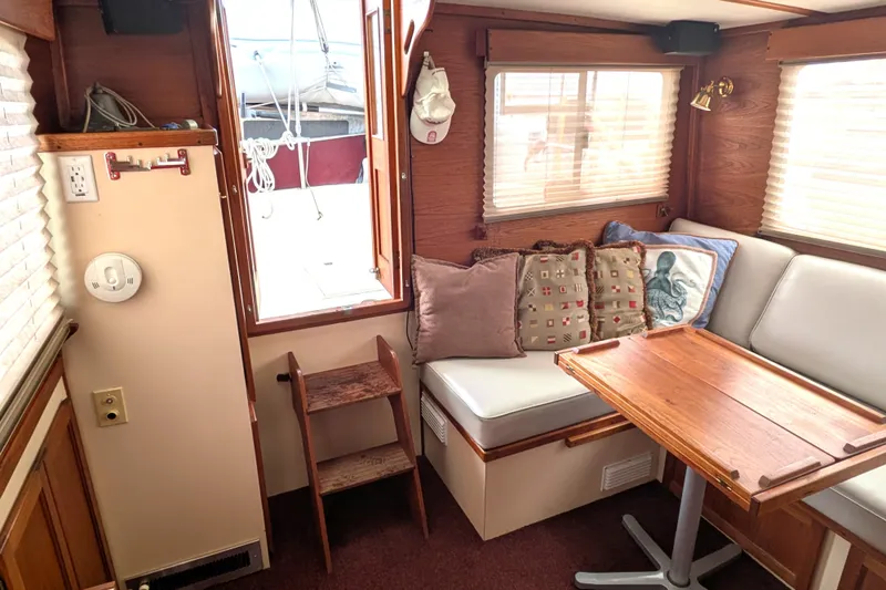 Slide: The Image of Cozy interior of a 1993 Nordic Tug 32 with wooden table and cushioned seating. - 13