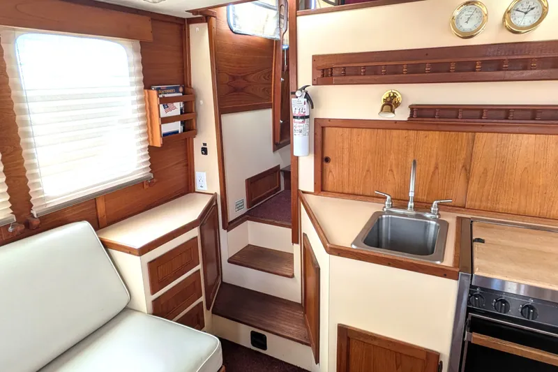 Slide: The Image of Interior of a 1993 Nordic Tug 32, featuring a compact kitchen and cozy seating area. - 14