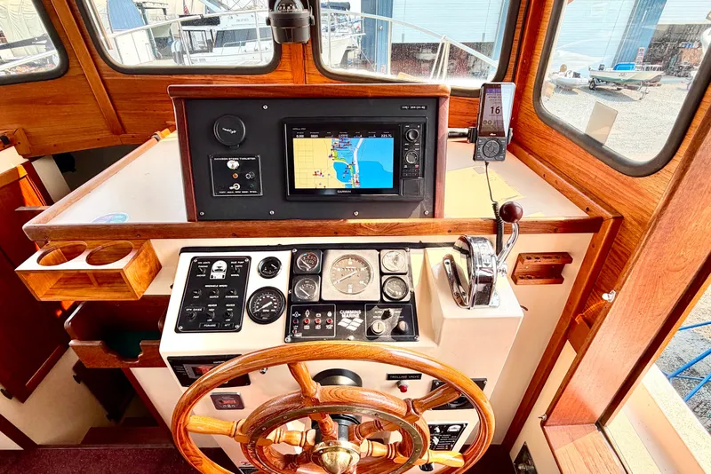 Slide: The Image of 1993 Nordic Tug 32 helm with wooden wheel, navigation instruments, and GPS display. - 25