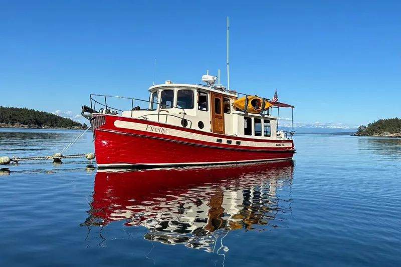 The Image of 1993 Nordic Tug 32 boat on calm water, reflecting clear blue sky and scenic landscape. - 0