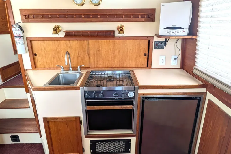Slide: The Image of Compact kitchen in a 1993 Nordic Tug 32, featuring a stove, sink, and mini fridge. - 18