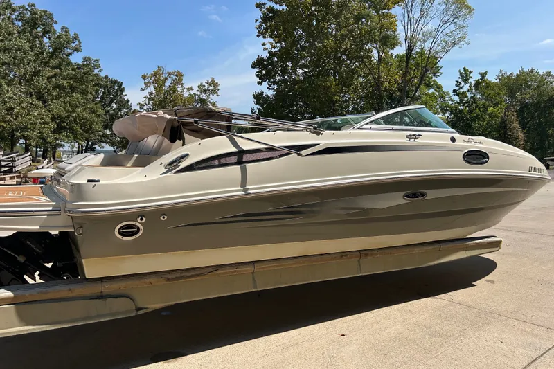 Slide: The Image of 2010 Sea Ray 260 Sundeck boat on trailer, surrounded by trees under clear sky. - 11